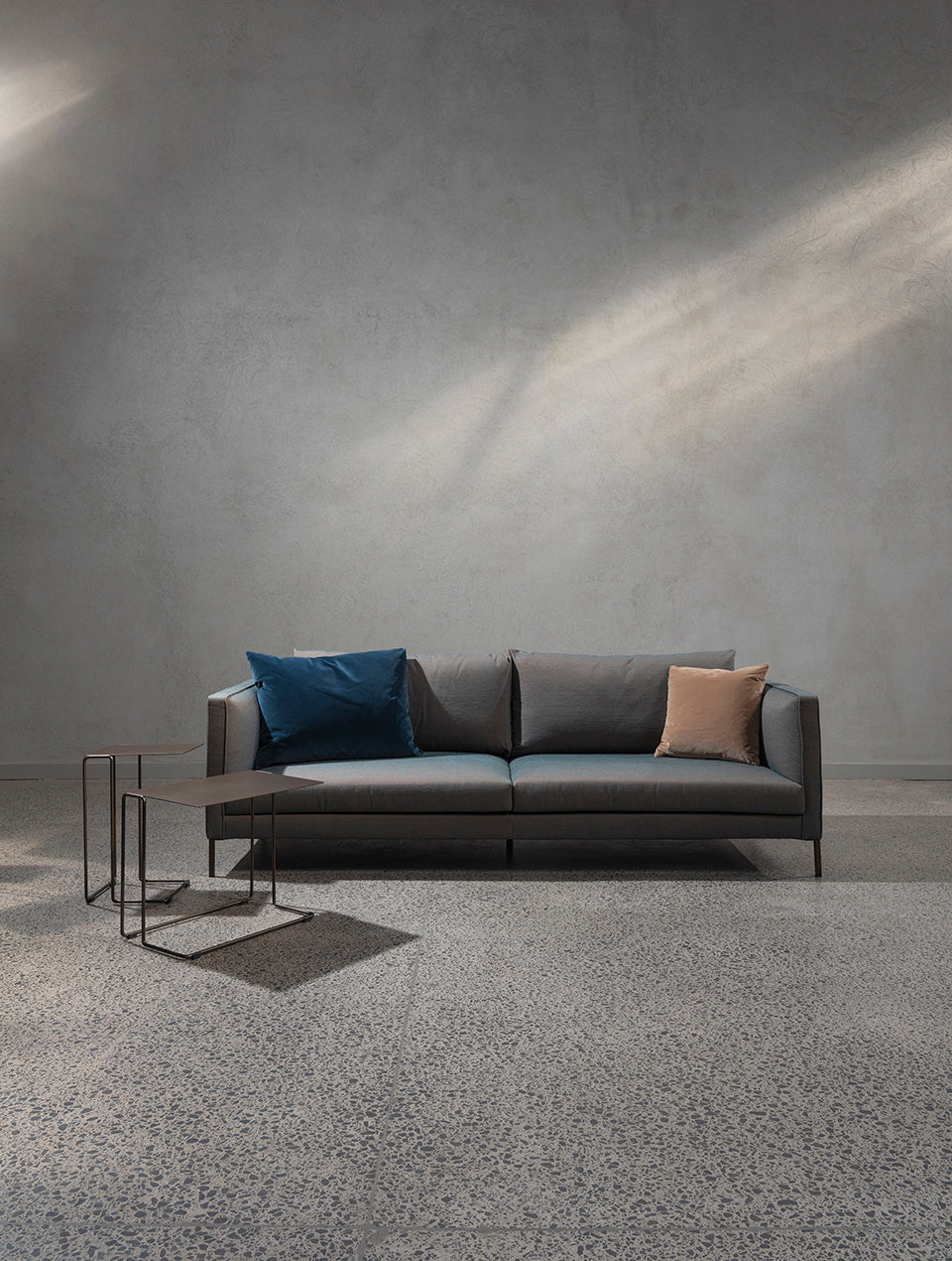Siena sofa in bronze and blue upholstery, styled with bronze Revello side tables on a polished concrete floor