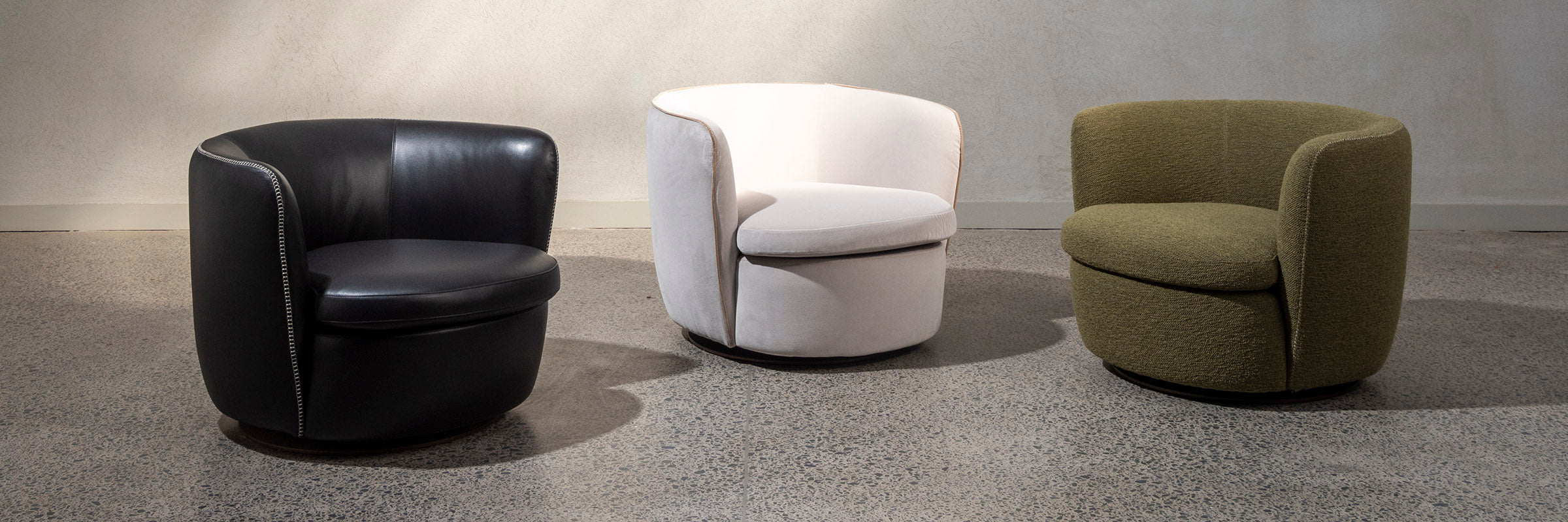 Bellagio arm chairs. Three in a row. One in black leather, two in fabric in white and green.