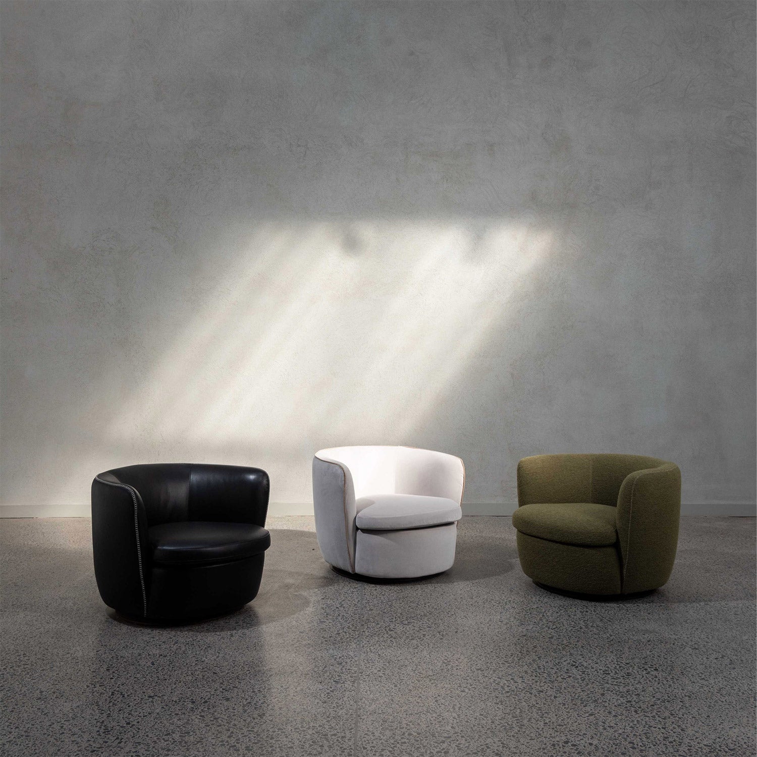 Three Italian Bellagio lounge chairs on showroom floor. One black, white and olive green.