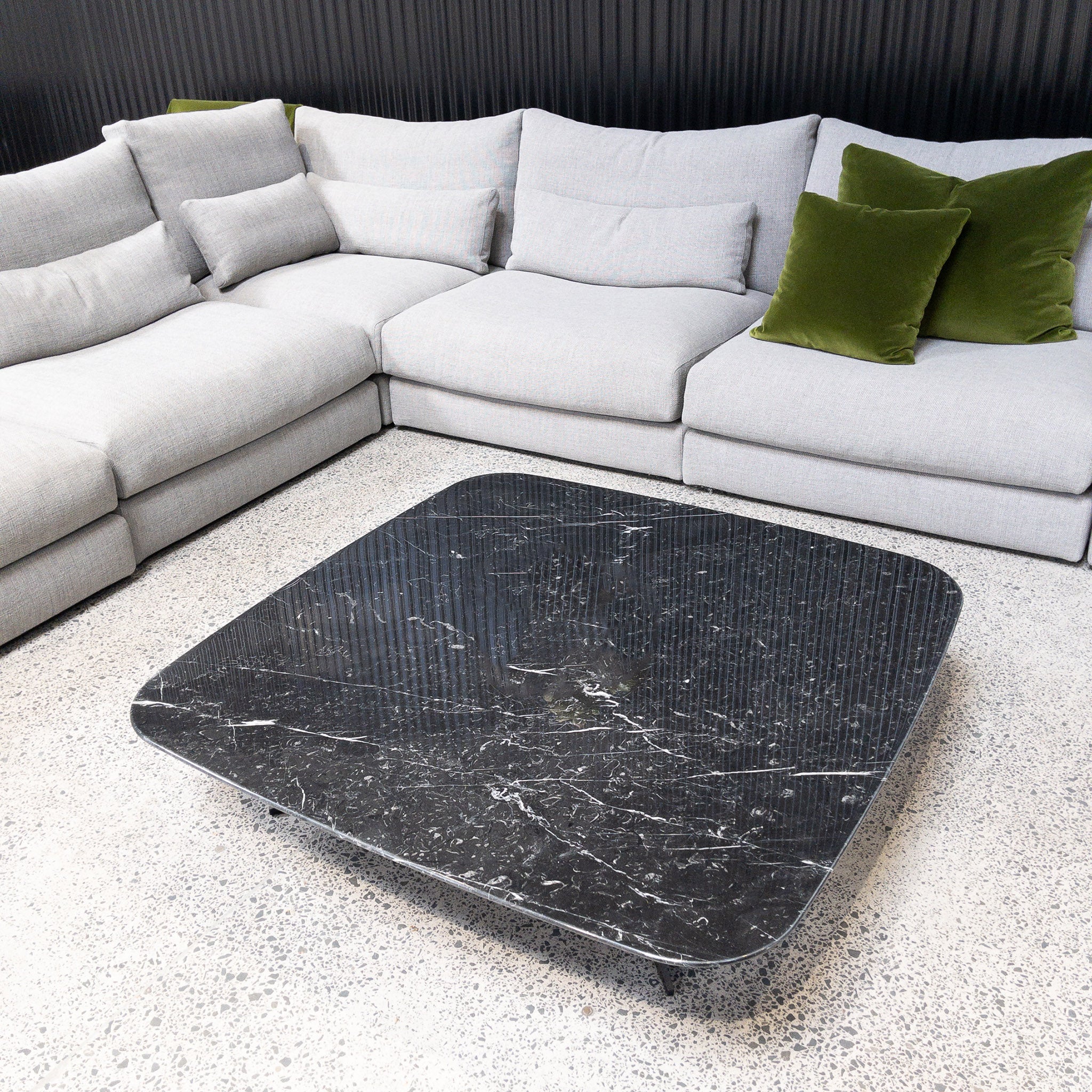Nero Marquinia black marble coffee table on showroom floor surrounded by modular furniture collection.
