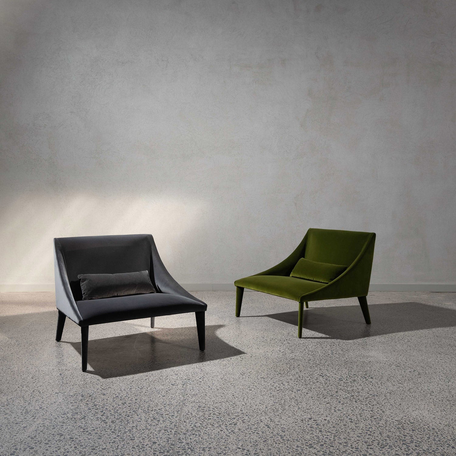 Two Petalo lounge chairs on showroom floor. One dark grey, the other olive green.