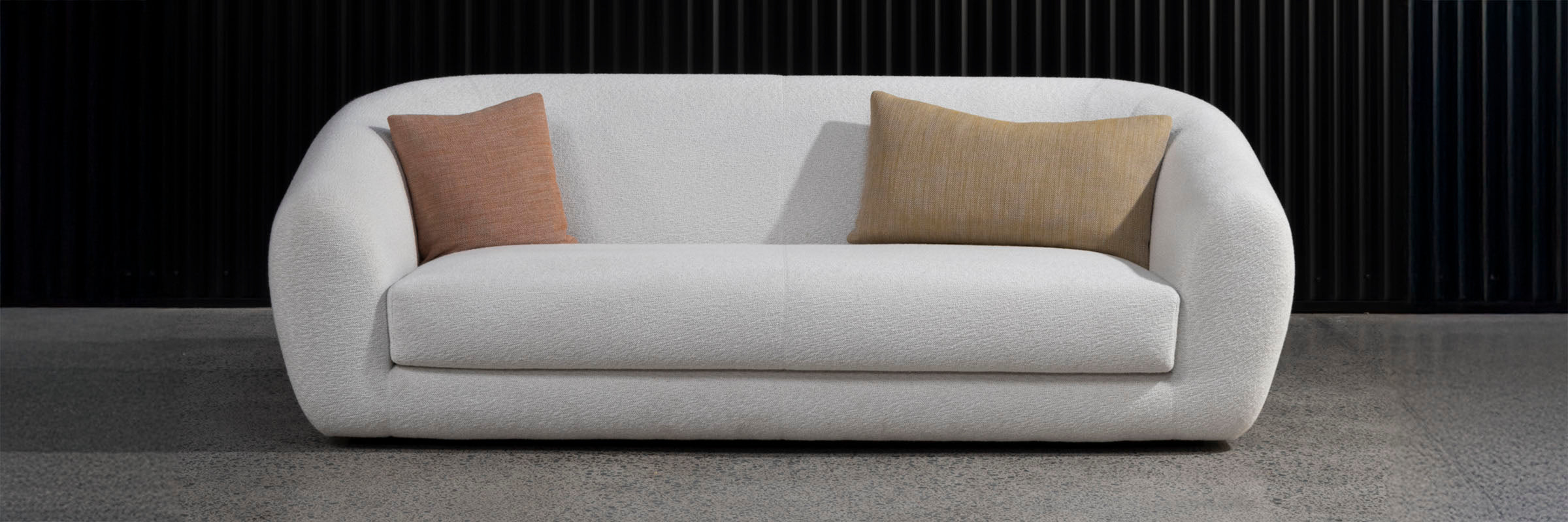 Showroom image of Pisa Plush 2 Seater Sofa in cream colour with two pillow cushions.