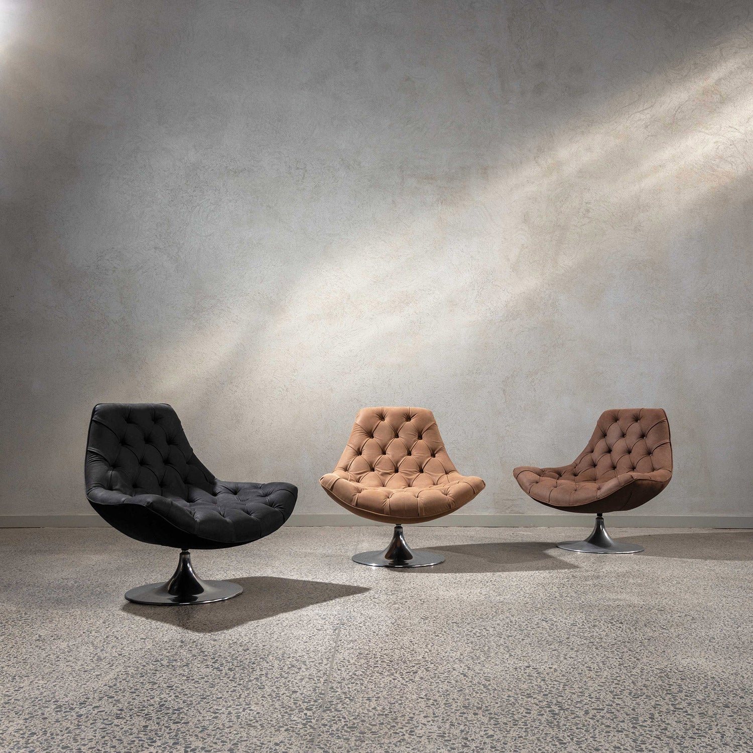 Three Italian Venezia lounge chairs on showroom floor. One in black, coffee colour and dark brown.