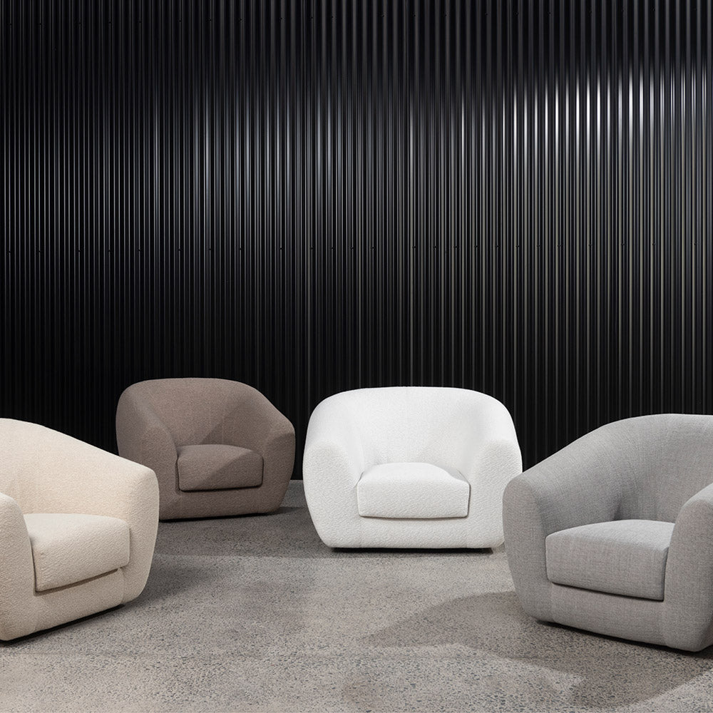 Four Pisa armchairs in textured neutral fabrics, arranged in front of a black fluted wall.